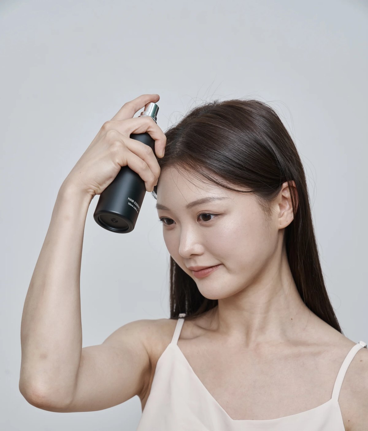 여성머리숱 고민으로 가르마에 두피 토닉을 뿌리는 장면